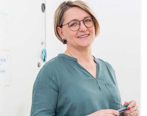 Manuela Kind vor einem großen Whitebord.